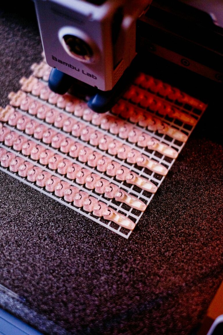 Close-up of 3D printer manufacturing small parts with intricate details in vibrant light.