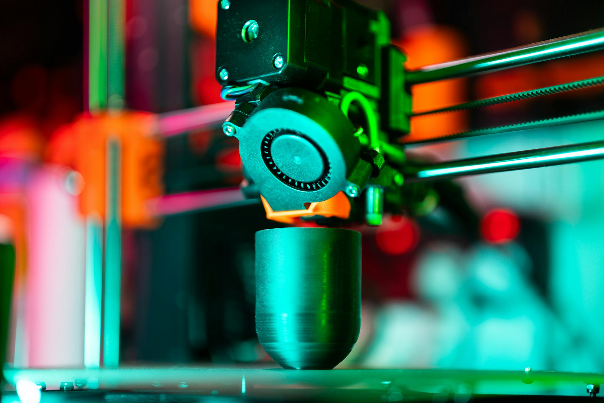 Close-up of a 3D printer creating a product in neon lighting.